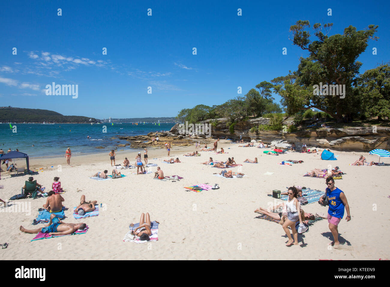 Junge Leute, die sich am Balmoral Edwards Beach in Mosman Sydney, New South Wales, Australien neben Rocky Point Island entspannen und sonnen Stockfoto