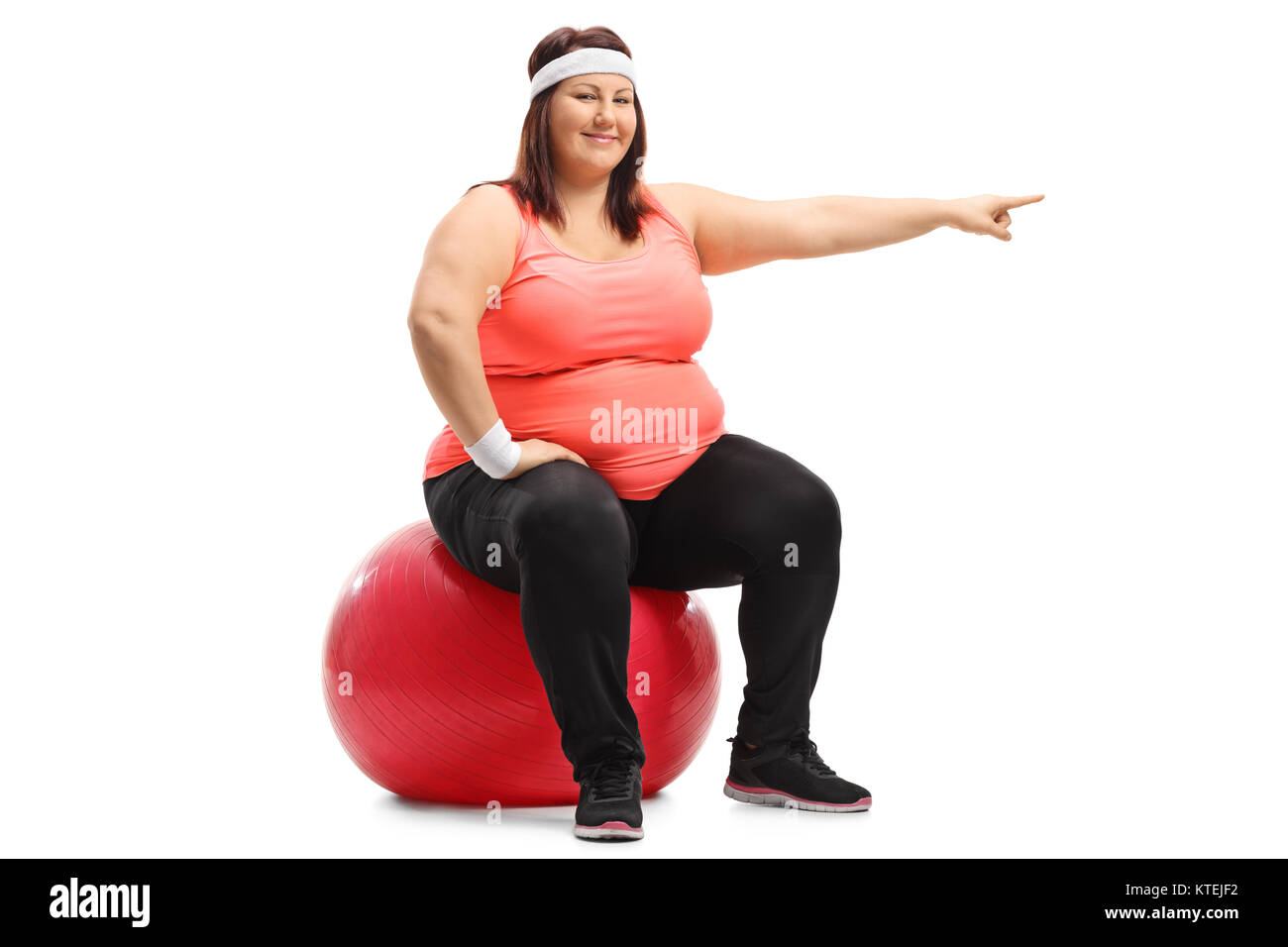 Übergewichtige Frau sitzt auf einem Pilates Ball und zeigen auf weißem Hintergrund Stockfoto