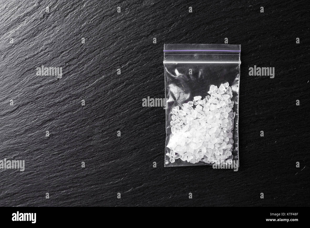 Drogen in der Form von Kristallen auf schwarzem Hintergrund, methamphetamine in einem Plastikbeutel Stockfoto