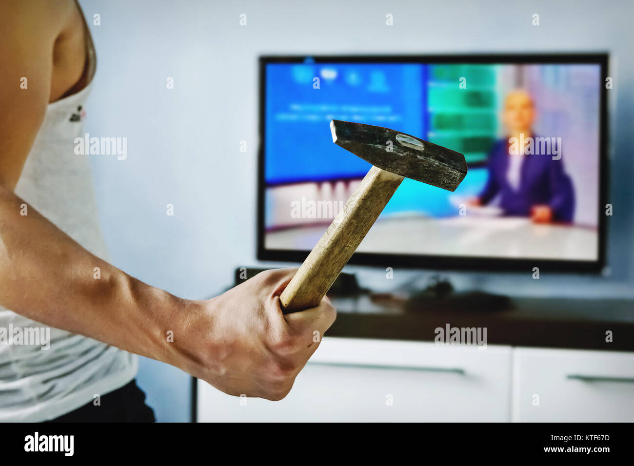 Der junge Mann die schlechten Nachrichten der TV mit einem Hammer bricht geärgert. Ein psychopath Beats TV. Verärgerte Viewer. wütend, wütend, rasender, verrückt, infuri Stockfoto