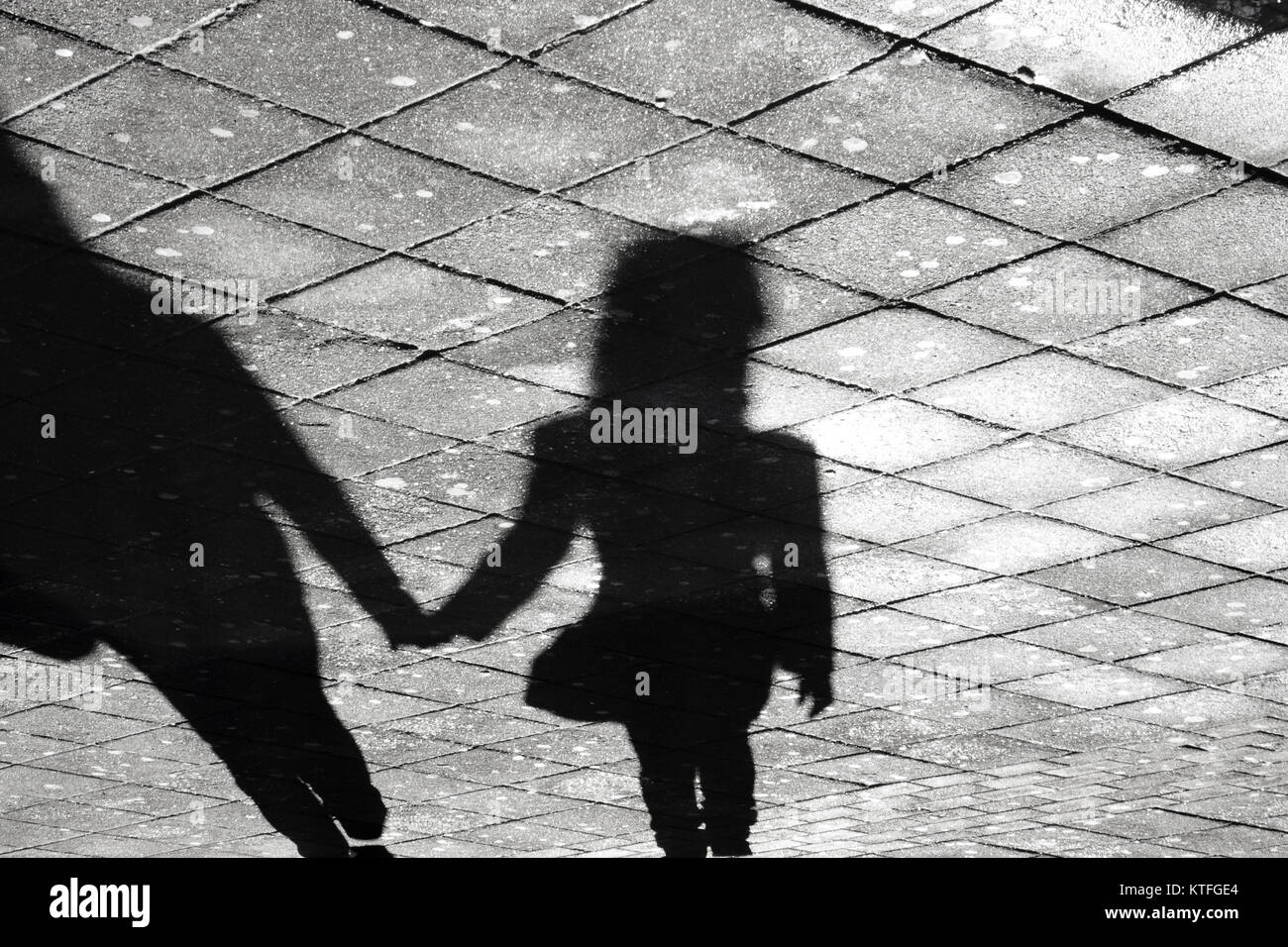 Mutter und Tochter halten sich an den Händen Schatten, die auf Stadt Straße Bürgersteig in Schwarz und Weiß Stockfoto