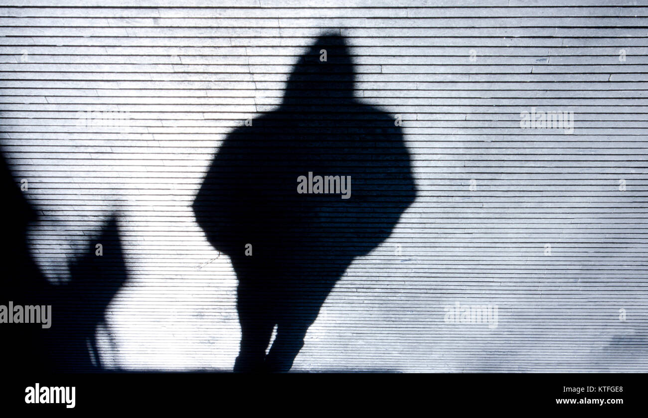 Verschwommene Schatten einer Person trägt eine Kapuze walking city street in Schwarz und Weiß Stockfoto