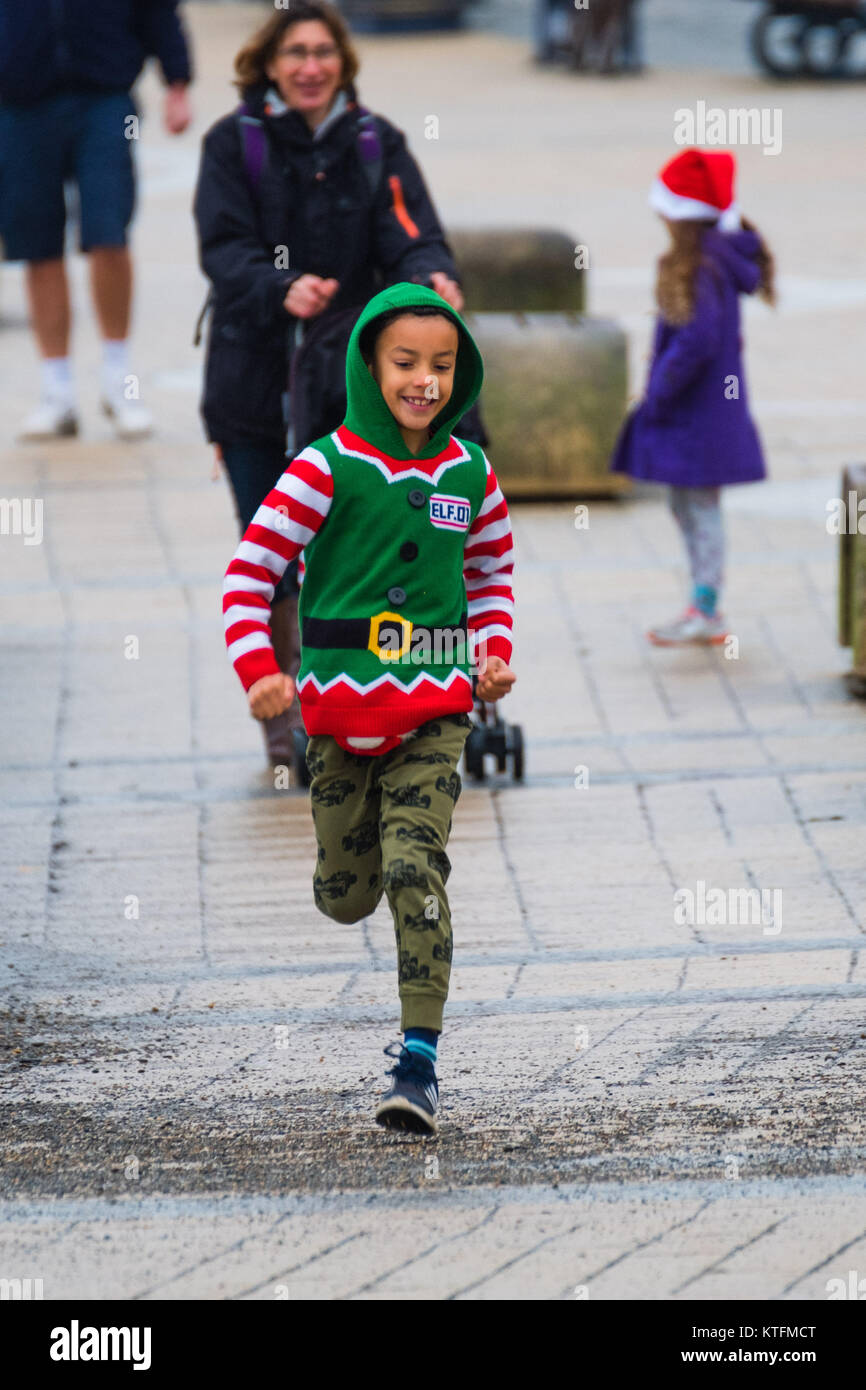 Aberystwyth Wales UK, Heiligabend, Sonntag, den 24. Dezember 2017 Großbritannien Wetter: Ein kleiner Junge gekleidet wie Santa's Helper glücklich auf der Strandpromenade in Aberystwyth Wales auf einen bemerkenswert mild, aber bewölkt und feucht, Heiligabend. Temperaturen über viel ofg Großbritannien in der 10-12°C reichen heute sein wird, bevor Sie wesentlich kälter und windiger, später in der Woche Foto © Keith Morris Credit: Keith Morris/Alamy leben Nachrichten Stockfoto