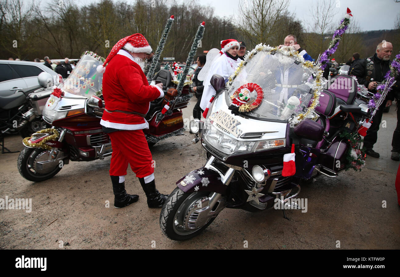 Hagen, Deutschland. 24 Dez, 2017. Ein Motorradfahrer gekleidet wie Santa  neben einem festlich geschmückten Motorrad an einem Biker treffen sich am  Hengsteysee Reservoir in Hagen, Deutschland, 24. Dezember 2017. Die Biker  immer