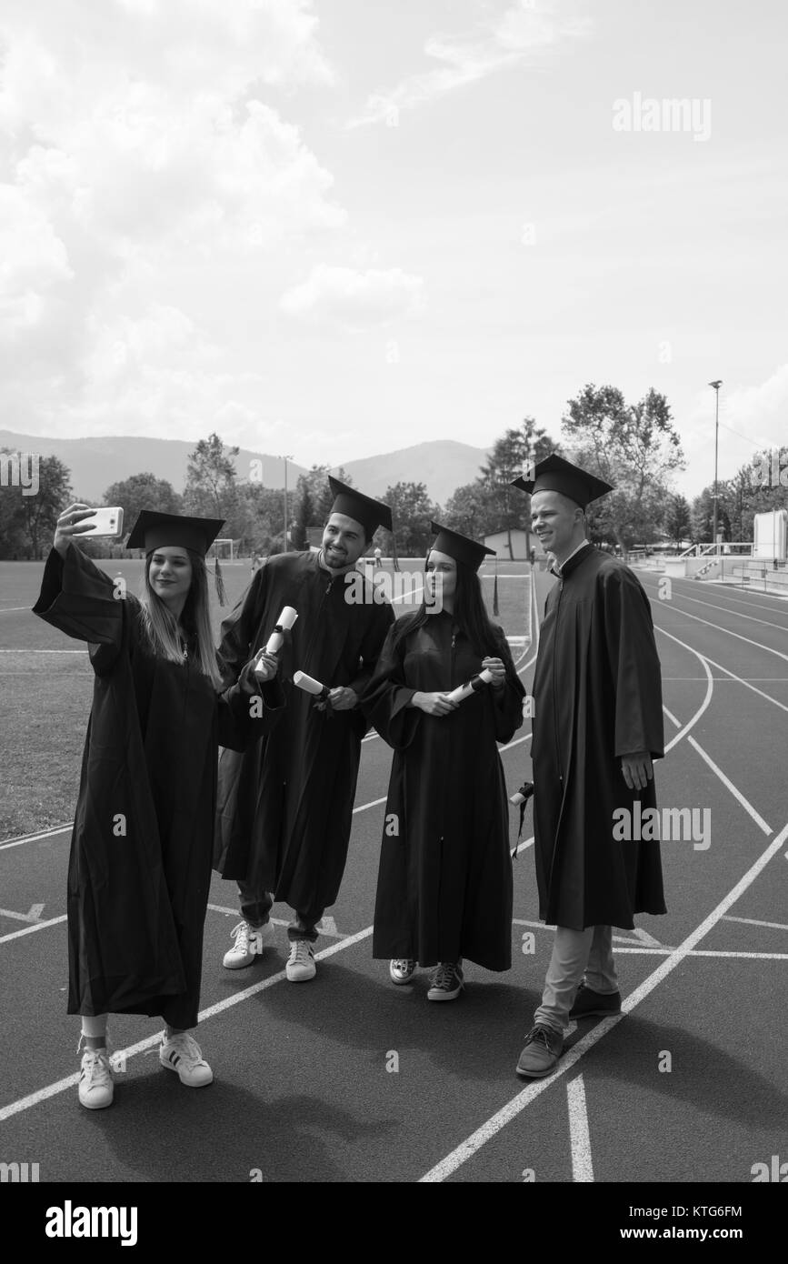 Bildung, Graduierung und Personen Konzept - Gruppe von Happy internationale Studierende in Mörtel Boards und Bachelor- Kleider mit den Diplomen Stockfoto