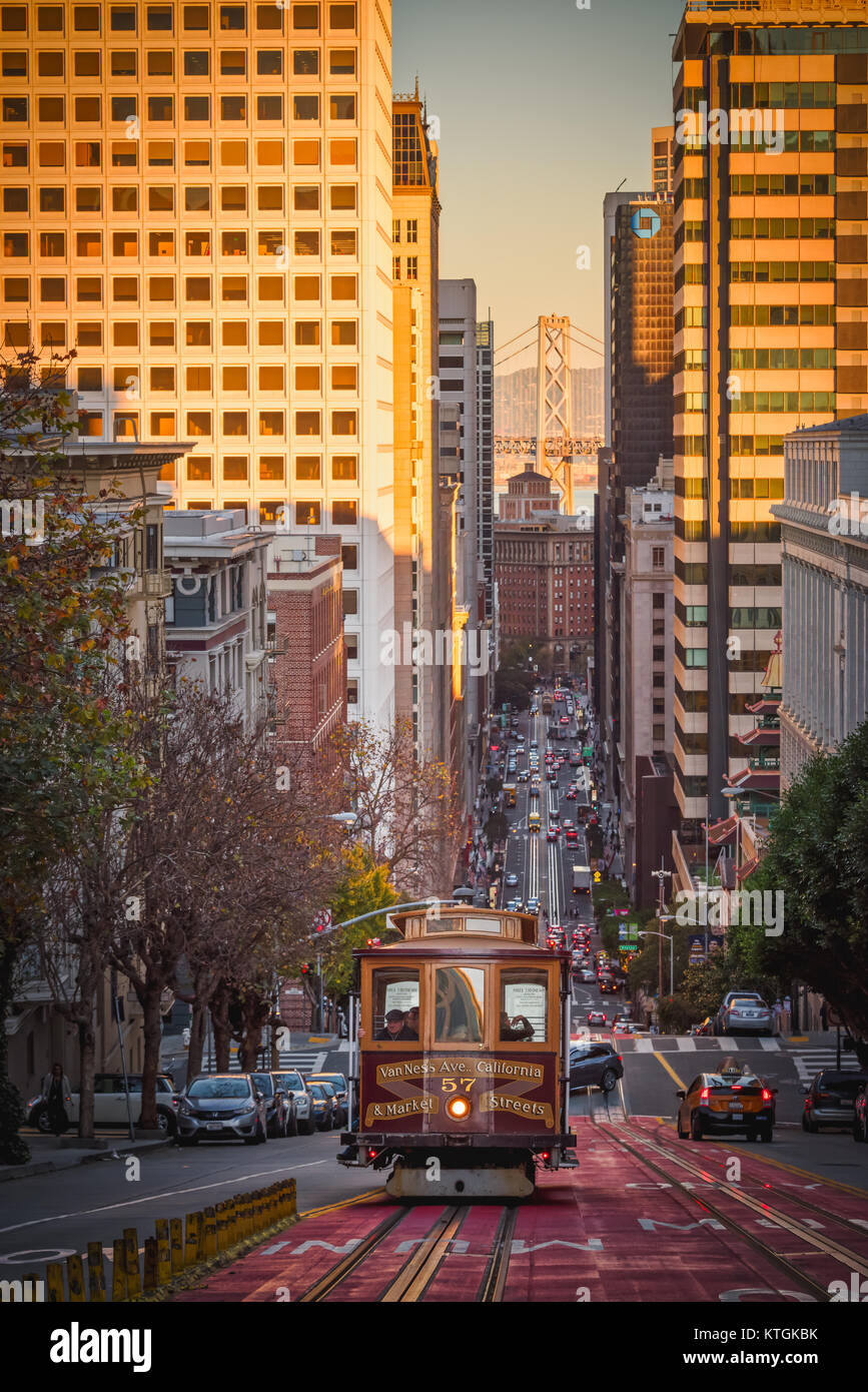 Cable Car in San Francisco kriechen auf dem Hügel; Bay Bridge im Hintergrund Stockfoto
