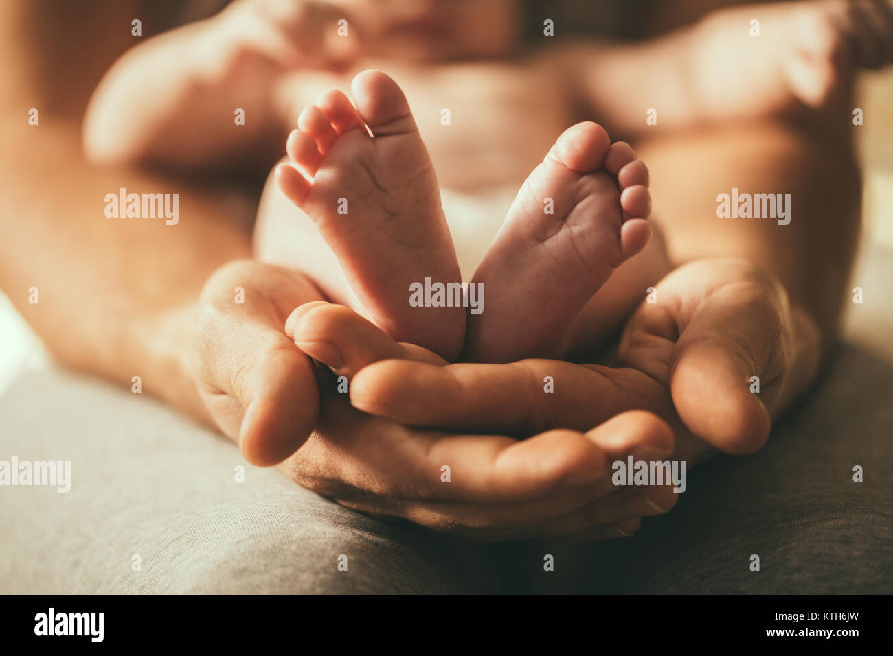 Mutter des neugeborenen Babys Füße. Kleine Füße in der Hand der Frau. Stockfoto