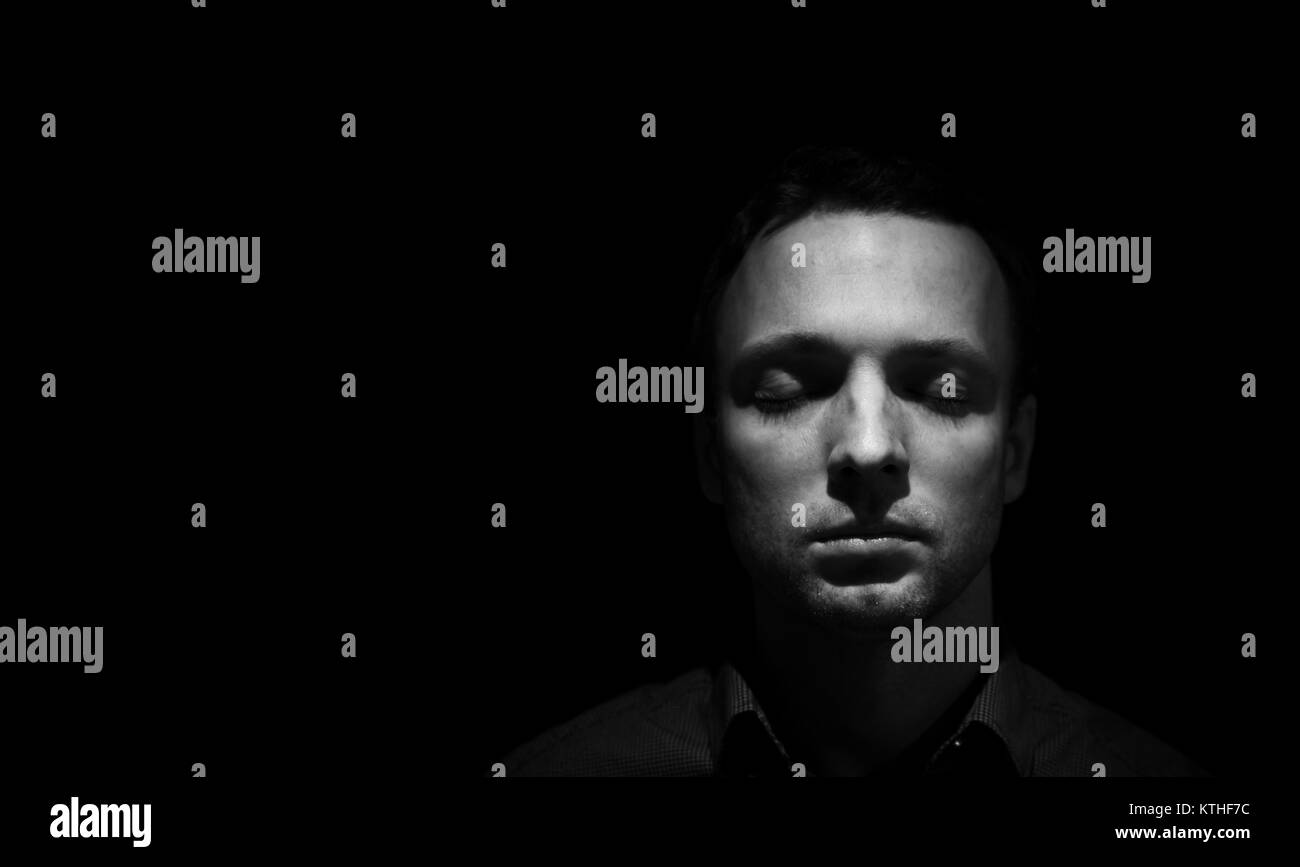 Closeup studio Gesicht Porträt der jungen Erwachsenen europäischen Mann mit geschlossenen Augen über schwarzen Hintergrund isoliert, Low Key Schwarz und Weiß Foto Stockfoto