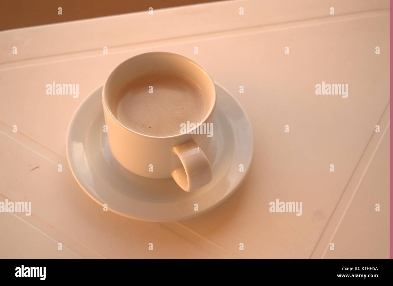 Eine warme bitteren Kaffee auf einem weißen Tisch mit einem Löffel und Untertasse unter warten auf jemanden, der sie in einen clod Wetter im Dezember 2017 zu trinken. Stockfoto