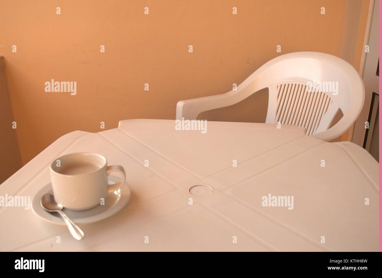 Eine warme bitteren Kaffee auf einem weißen Tisch mit einem Löffel und Untertasse unter warten auf jemanden, der sie in einen clod Wetter im Dezember 2017 zu trinken. Stockfoto