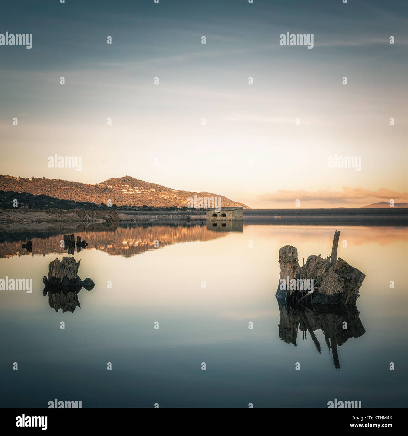 Abgebrochene Stein bergerie Gebäude und Baumstümpfen offenbart und in der niedrigen wider, noch Wasser des Lac de Codole in Reginu Tal in der Balagne Stockfoto