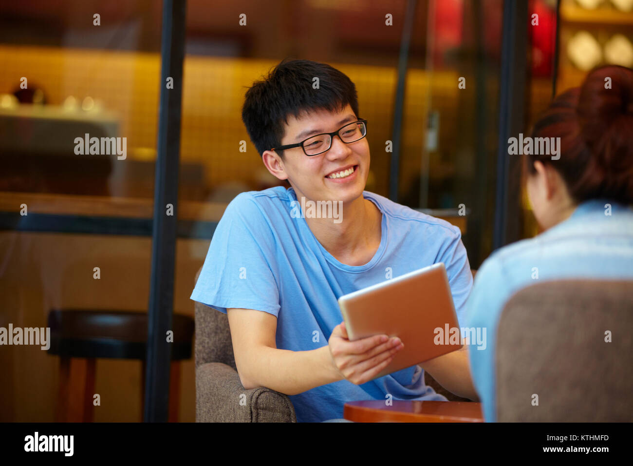 Chinesischen jungen Mann mit Tablette im Cafe mit seiner Freundin Stockfoto