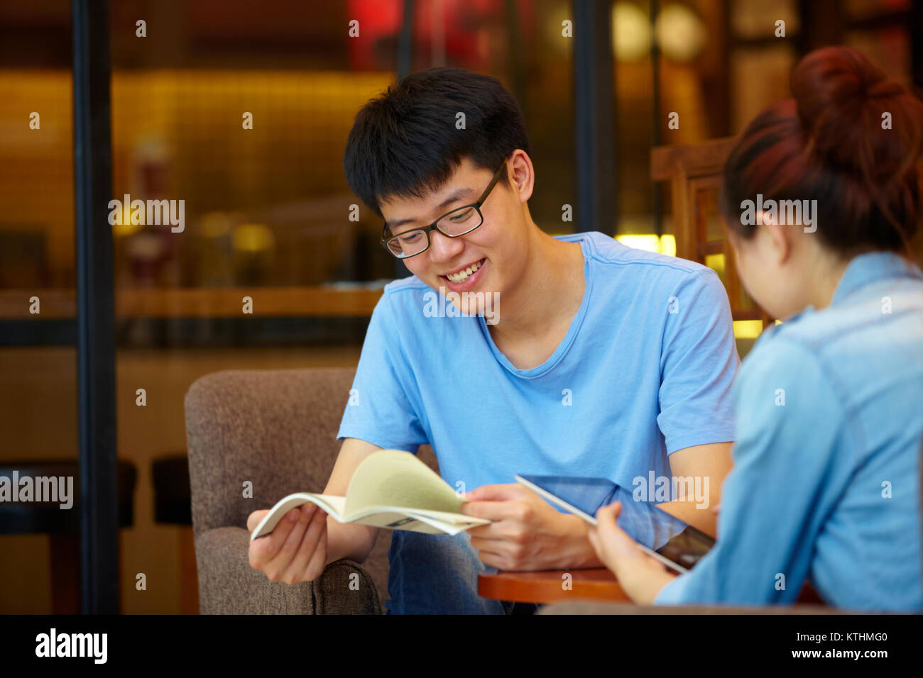Chinesischen jungen Mann mit Tablette im Cafe mit seiner Freundin Stockfoto