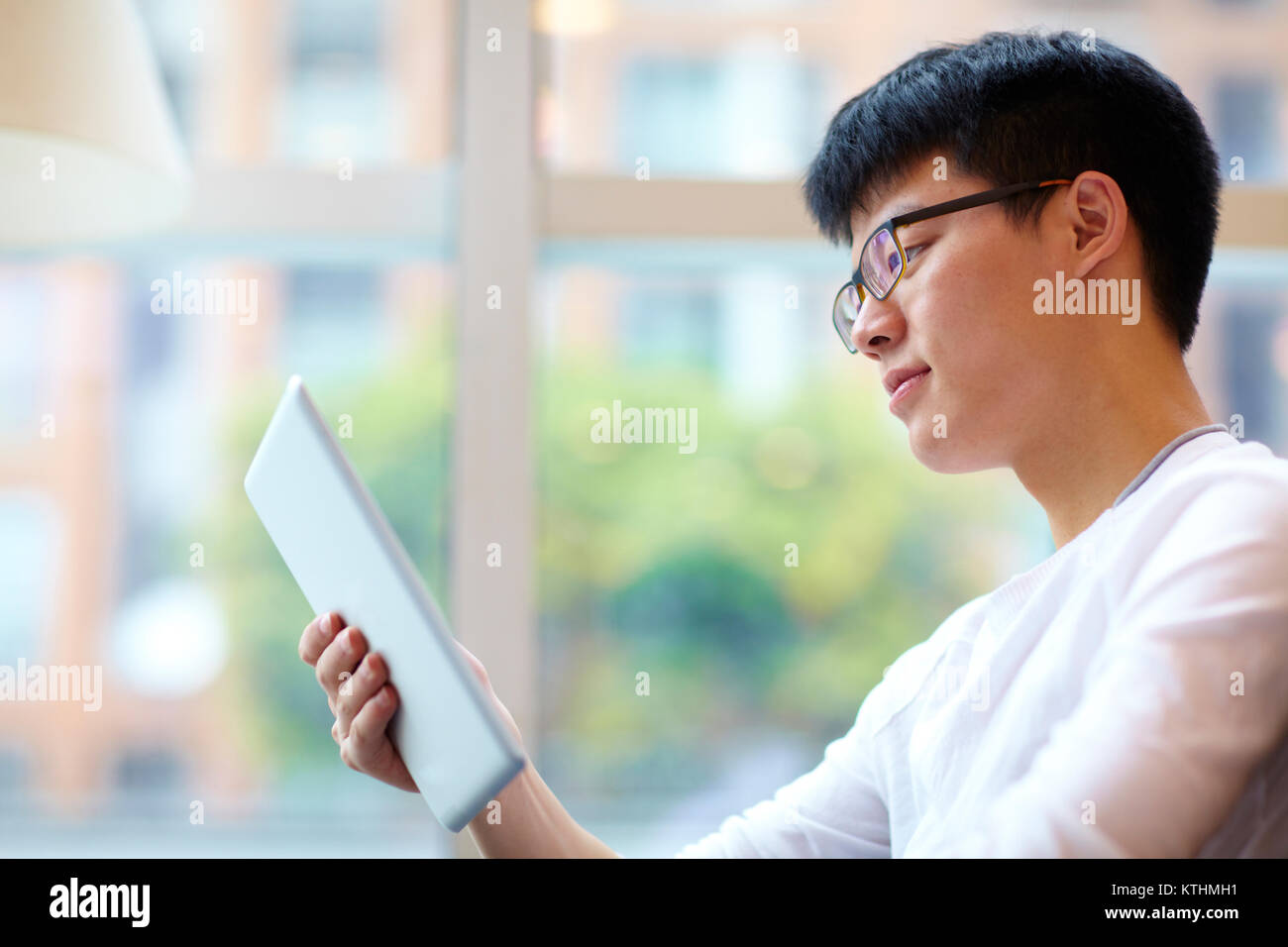 Chinesischen jungen Mann mit Tablette im Cafe Stockfoto