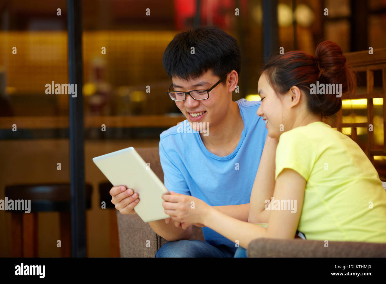 Chinesischen jungen Mann mit Tablette im Cafe mit seiner Freundin Stockfoto
