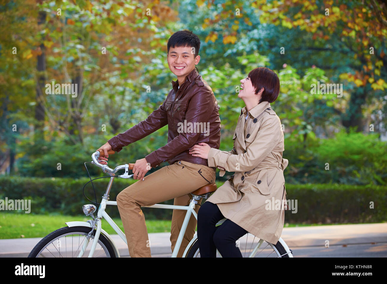 Zwei junge chinesische Studenten sitzen auf dem Fahrrad auf dem Unternehmensgelände Stockfoto