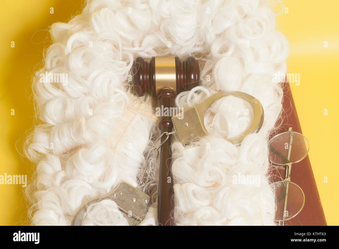 Für Richter: Richter Perücke, handcluffs, Richter Hammer, Buch Ende Brillen auf gelbem Hintergrund Stockfoto