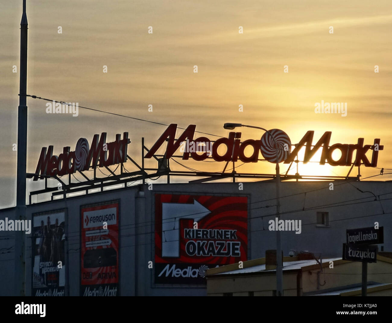 Dieses Bild zeigt die leuchtenden Neonschilder von MediaMarkt, einem beliebten Elektrofachgeschäft, das sich in einer urbanen Umgebung befindet und die moderne Einzelhandels- und Unterhaltungselektronik symbolisiert. Stockfoto