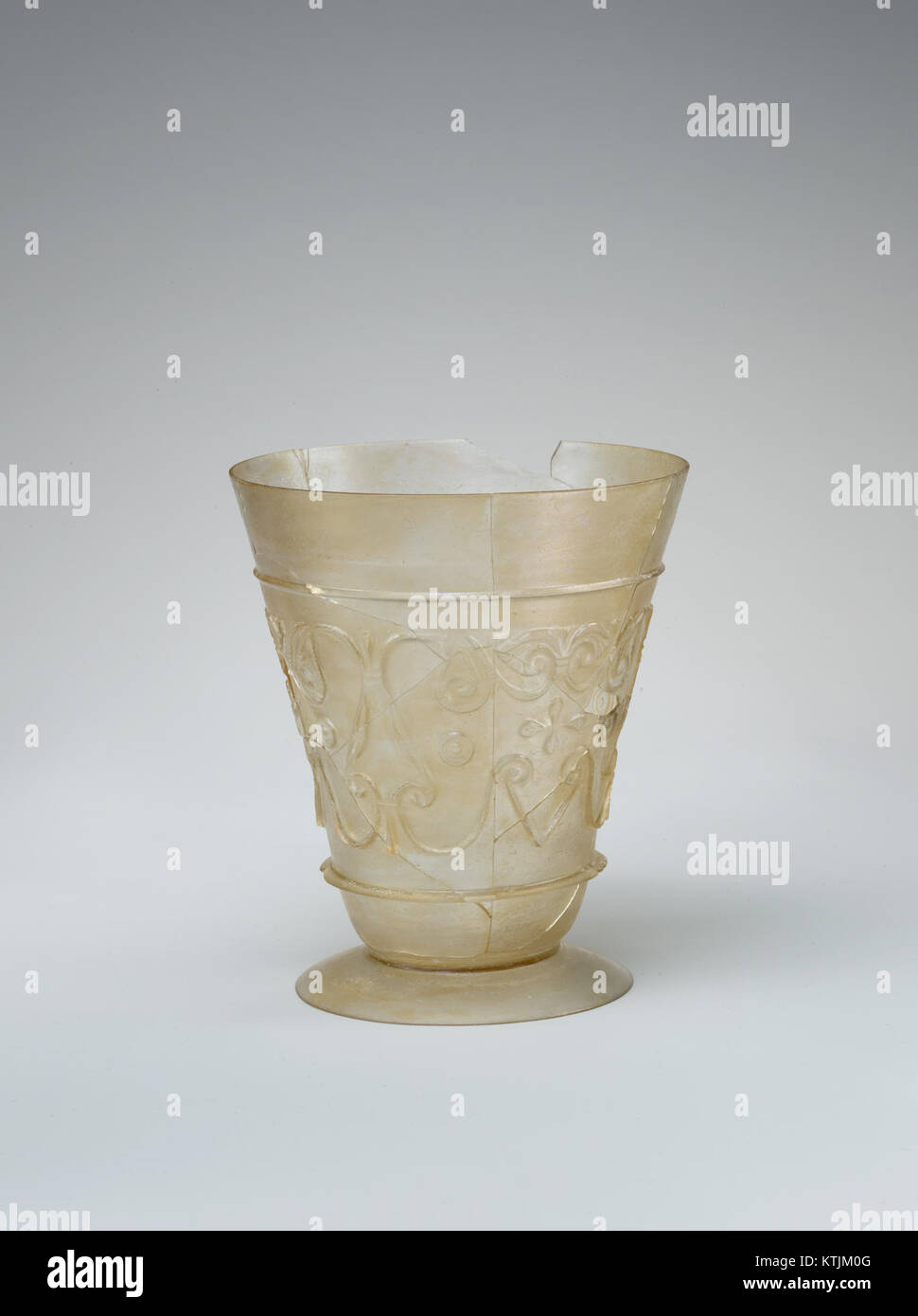 Ein Glasbecher aus dem 9. Bis 10. Jahrhundert aus dem Iran mit aufwändigen Reliefverzierungen. Das transparente, farblose Glasgefäß zeigt die fortschrittliche Handwerkskunst dieser Zeit. Stockfoto