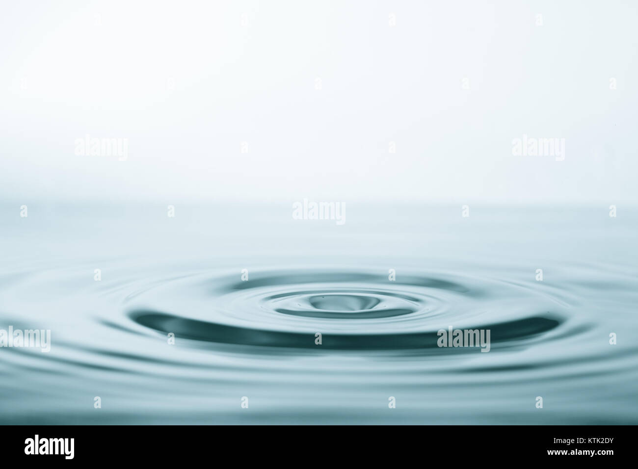 Wasser Tropfen und Spritzen auf Wasseroberfläche auf blauem Hintergrund Stockfoto
