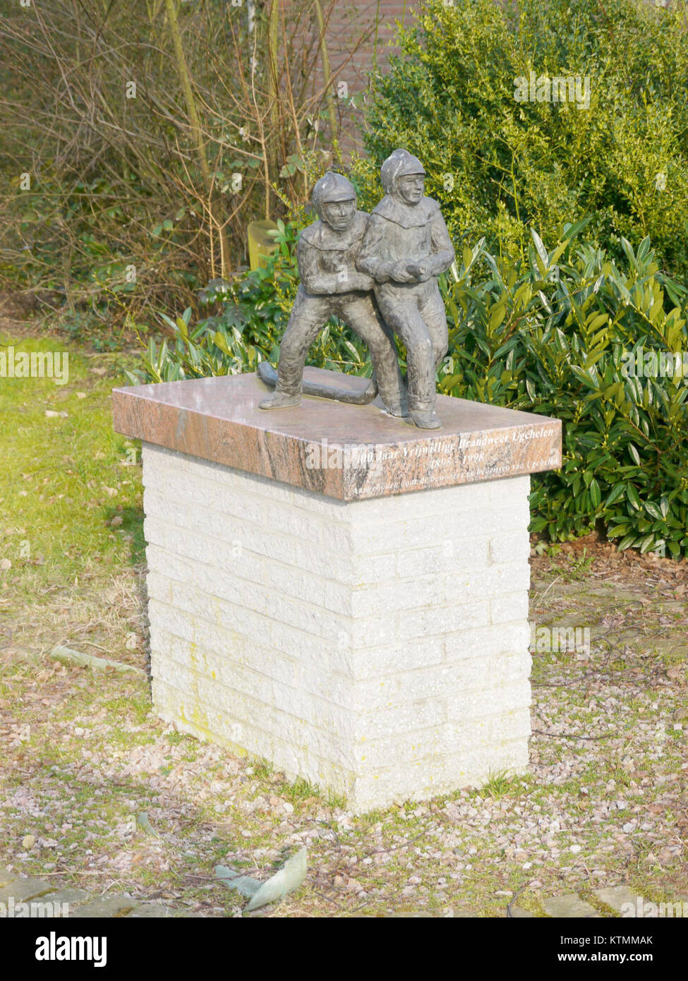 Eine Gedenkstatue zum 100-jährigen Bestehen der Freiwilligen Feuerwehr in Ugchelen, Niederlande. Das Denkmal ehrt die Widmung der Feuerwehrleute, die der Gemeinde dienen. Stockfoto