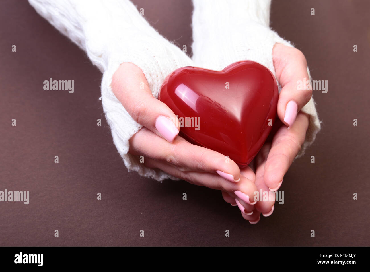 Weibliche Hände geben rotes Herz auf Gold Hintergrund isoliert, Weihnachten Winter Liebe Stockfoto