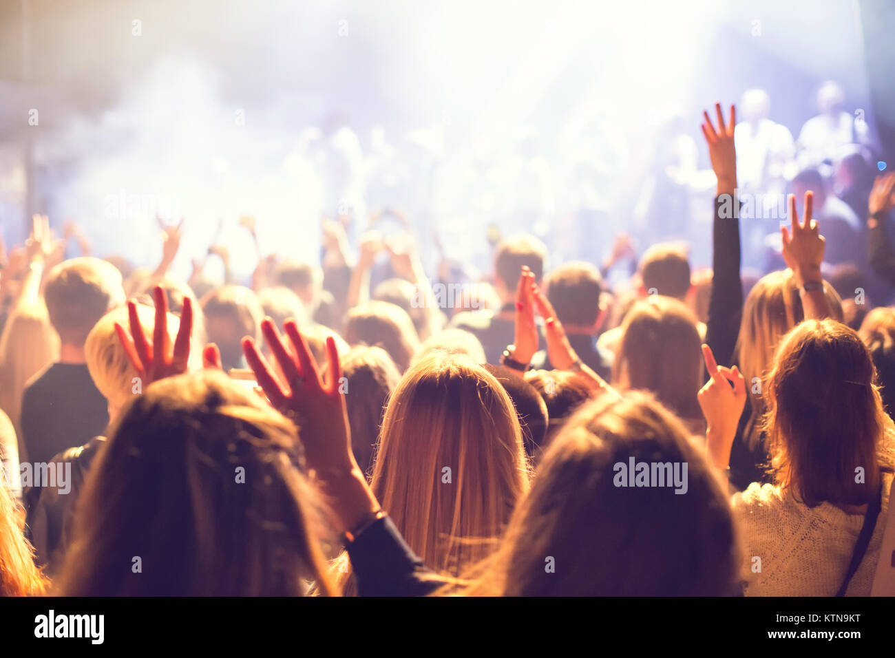Eine Masse von Zuschauern bei einem Konzert in einem kleinen Konzert Club. Klatschen und Tanzen in der Nähe der Bühne. Das Publikum ist mit Licht gefüllt. Stockfoto