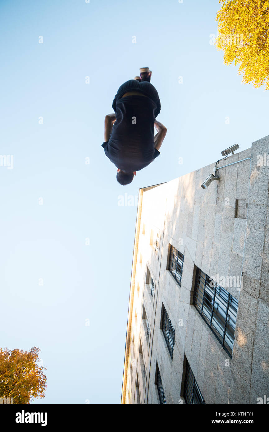 Junger Mann eine Seite blättern oder Salto beim Üben Parkour auf der Straße. Stockfoto