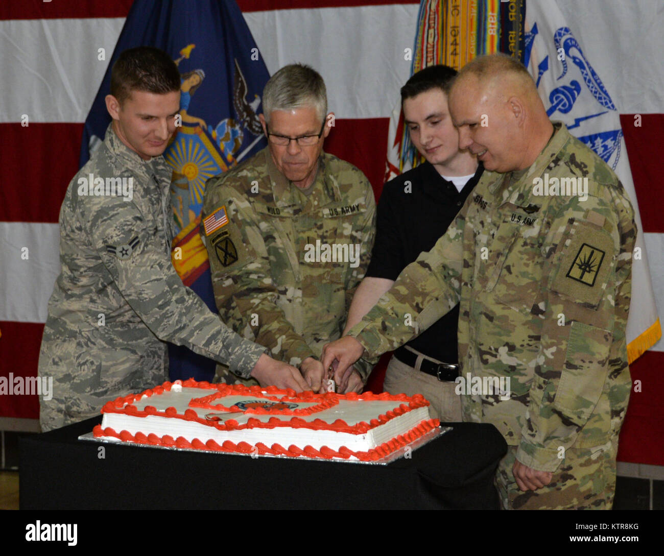 LATHAM, N.Y.-Brig. Gen. Raymond Schilde, stellvertretender Adjutant General, Armee, von New York (ganz rechts) verbindet die ältesten und jüngsten Mitglieder des New York National Guard einen Kuchen in der Feier des 380. Geburtstag des nationalen Schutzes an der New York National Guard Sitz hier am 04.12.13. Die Nationalgarde wurde im Jahre 1636 gegründet und ist die älteste militärische Kraft in der Abteilung für die Verteidigung. Die neuen und alten Mitglieder sind Pvt. Private Cameron Thompson, Alter 17, New York Army National Guard (Mitte rechts); Chief Warrant Officer 5 Robert Wold, einem der ältesten ser der New York Army National Guard Stockfoto