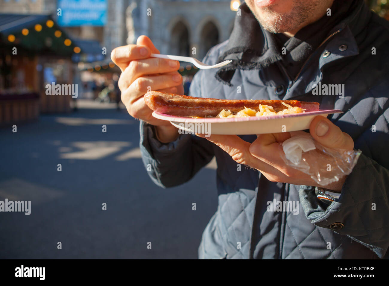 Der Mensch isst Würstchen und Sauerkraut aus einer Hütte an einem Wiener Weihnachtsmarkt Rathausplatz, 2017 Stockfoto