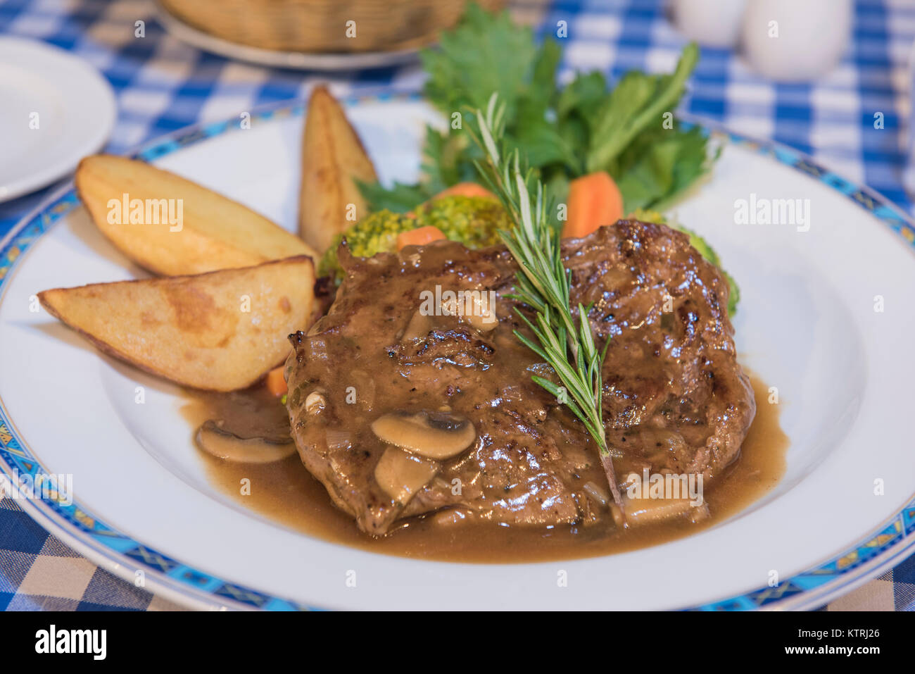 Rindersteak à-la-carte-Essen mit Pilzsauce auf weiße Platte im Restaurant Stockfoto