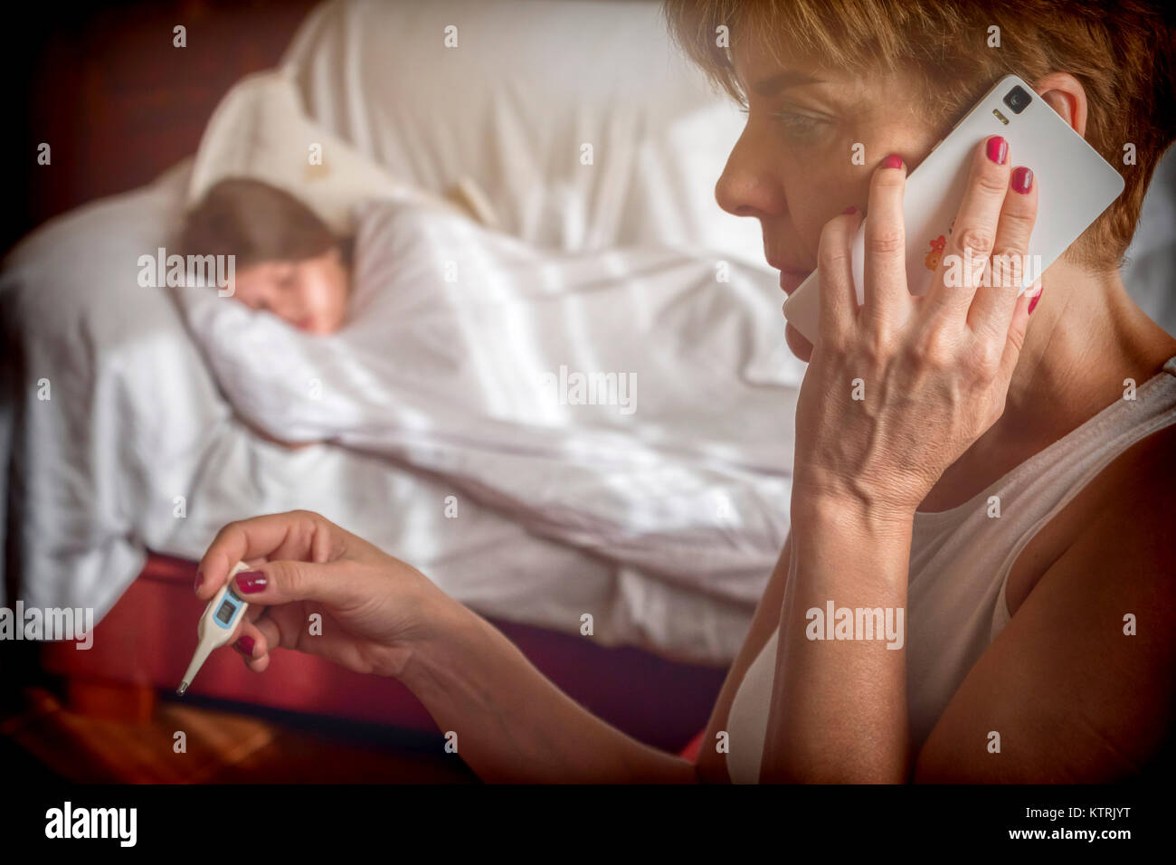 Frau mittleren Alters Aufruf per Telefon zum Krankenhaus mit Thermometer in der rechten Hand, die Tochter auf dem Sofa mit Fieber, konzeptionelle Bild Stockfoto
