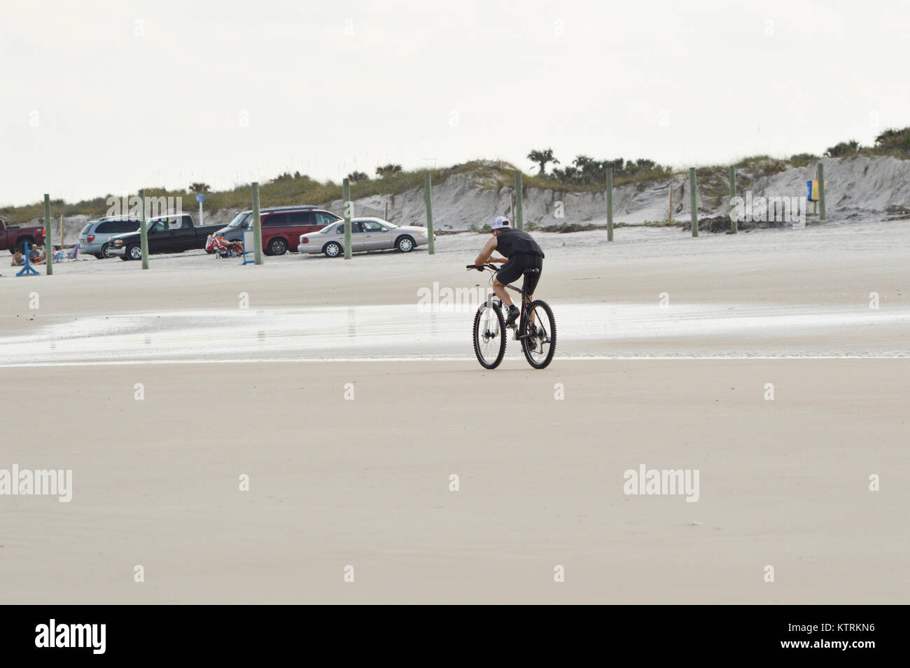 Ein Kerl Radtouren so schnell er kann unten am Strand an einem klaren und sonnigen Tag Stockfoto