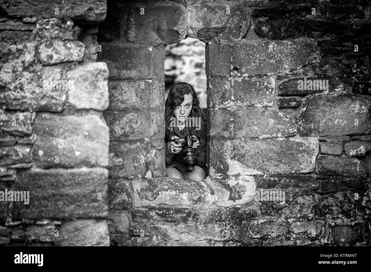 Junge Fotografin quetscht in kleine Öffnung an Middleham Castle, Wensleydale, in der Grafschaft North Yorkshire, England. Stockfoto