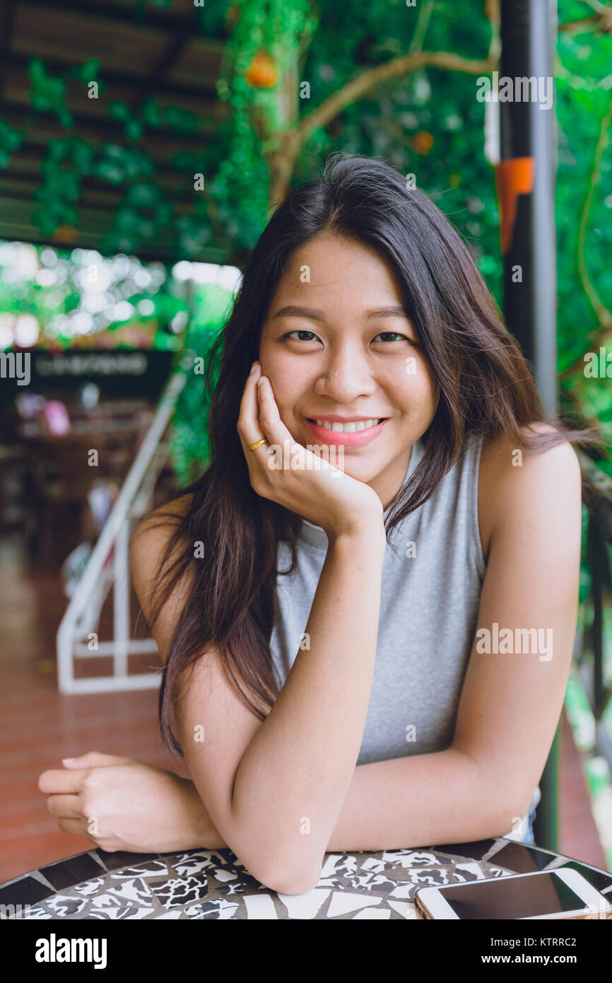 Süße asiatische Thai Frauen Porträt im Cafe Sitzhaltung mit zahnmedizinischen schönes Lächeln entspannen Stockfoto