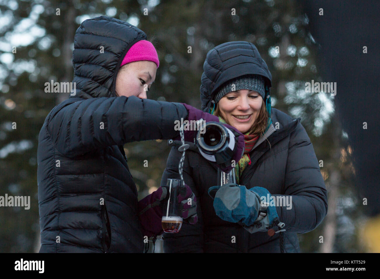 Zwei Frauen, die im Winter von drinnen nach draußen trinken Champagner Stockfoto