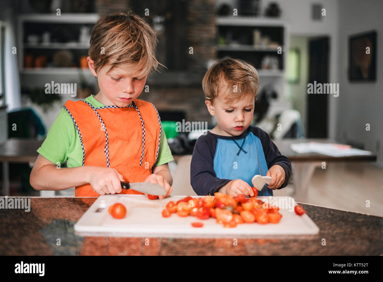 Zwei Jungen hacken Tomaten in der Küche Stockfoto