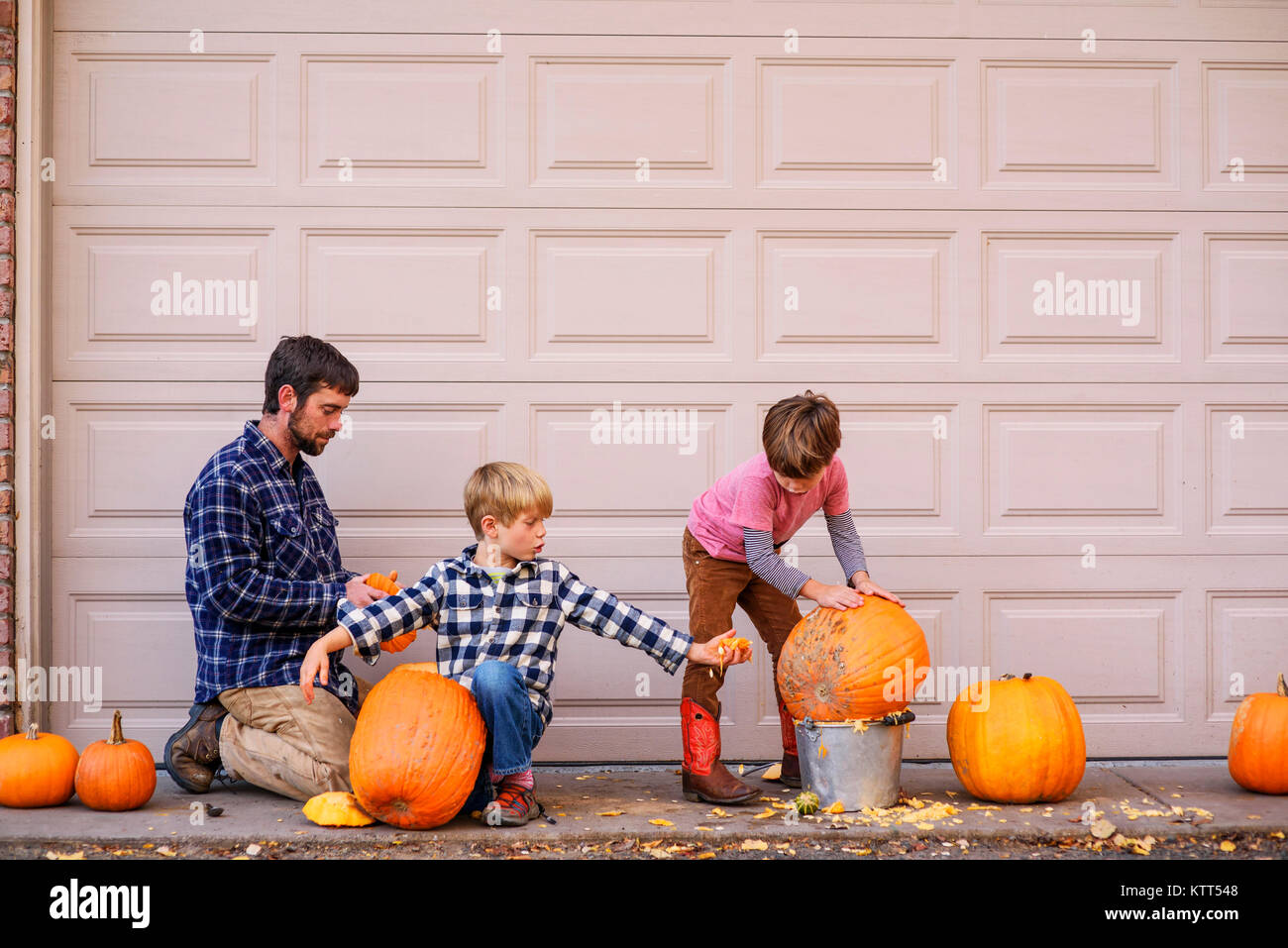 Zwei Jungs und ihr Vater schnitzen Halloween Kürbisse Stockfoto