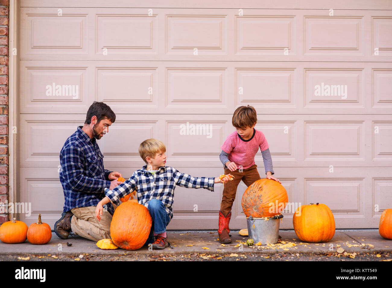 Zwei Jungs und ihr Vater schnitzen Halloween Kürbisse Stockfoto