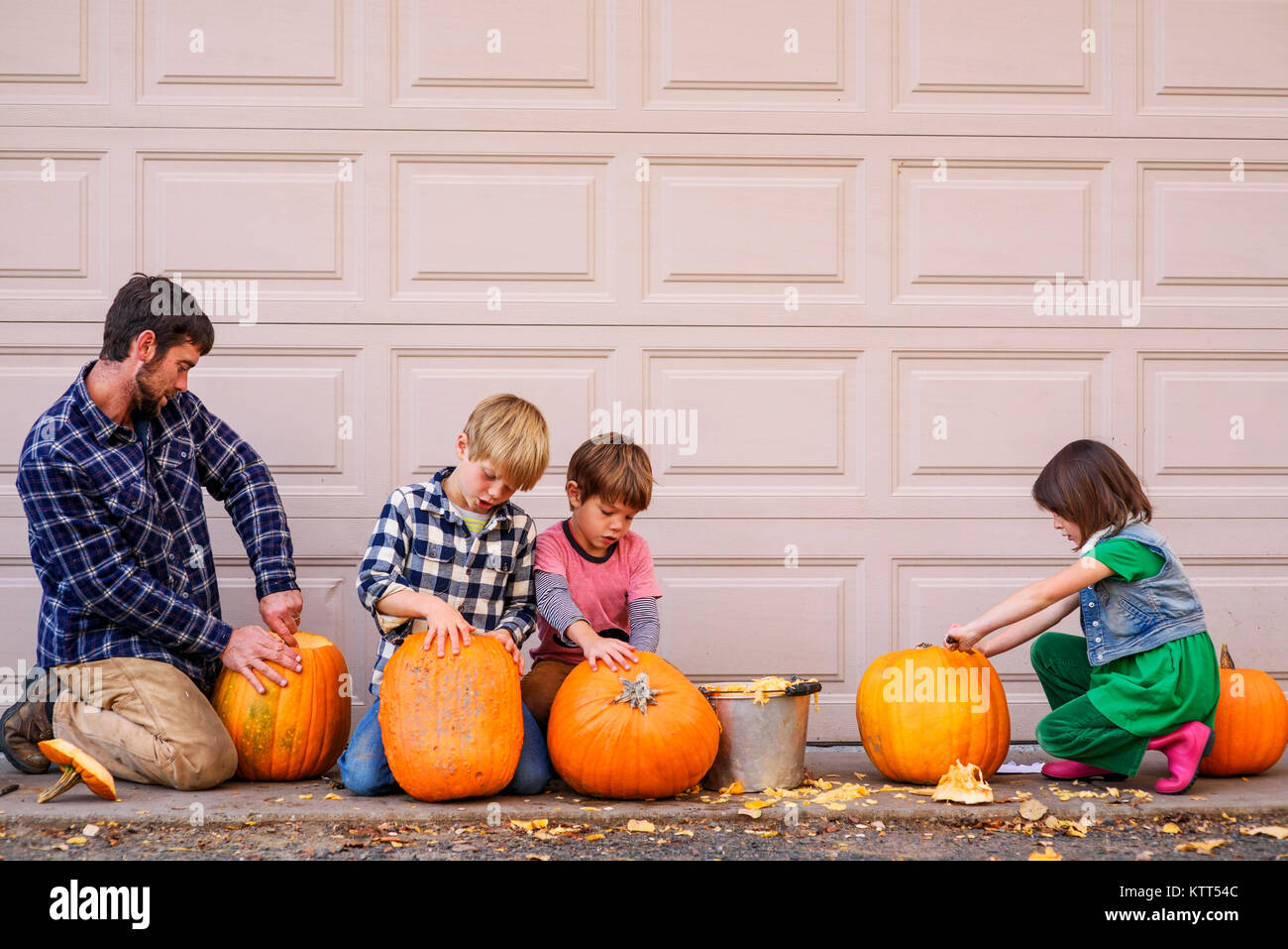Drei Kindern und ihrem Vater schnitzen Halloween Kürbisse Stockfoto