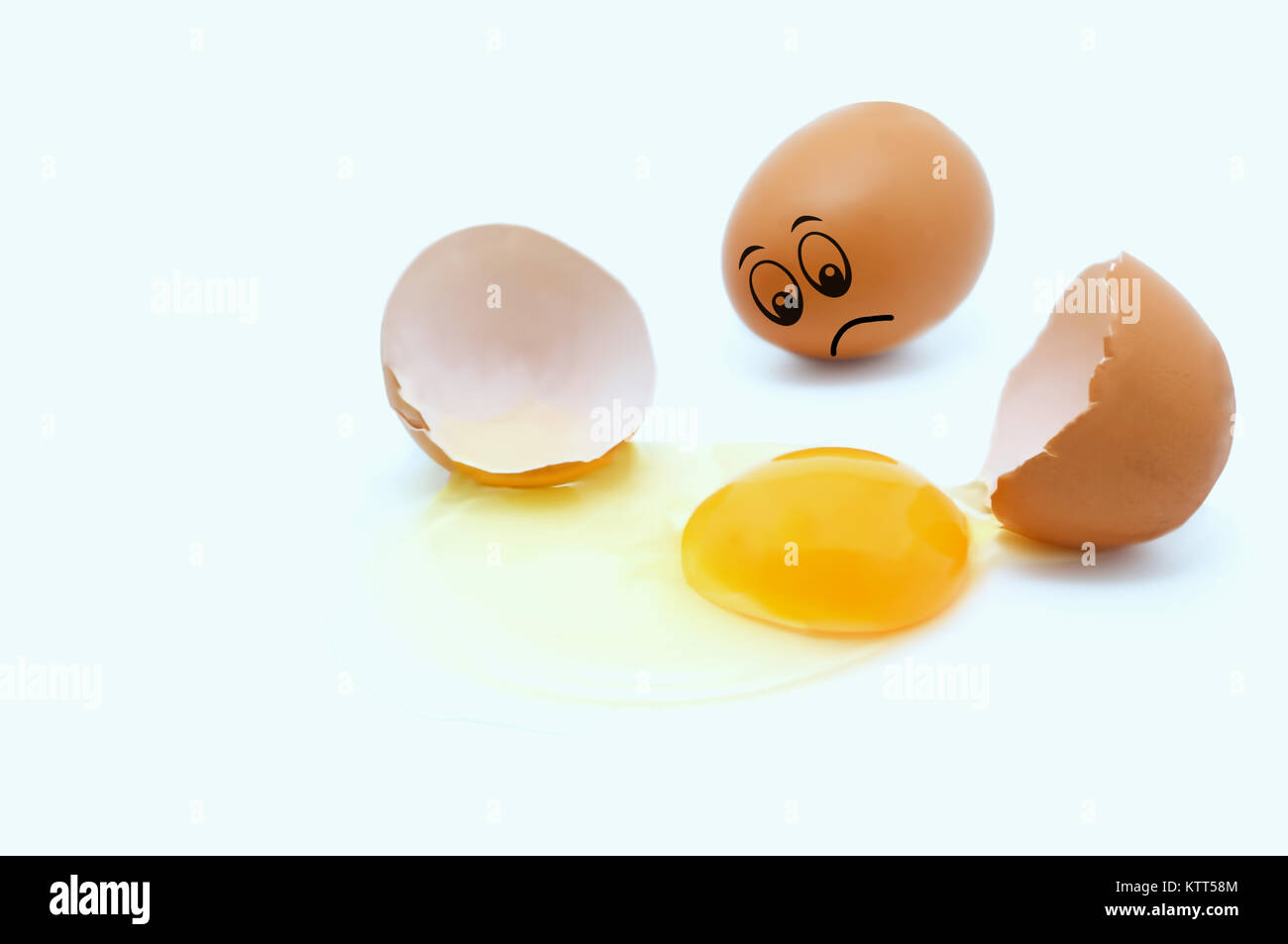 Gebrochene Eier und ein Ei mit einem traurigen Gesicht Stockfoto