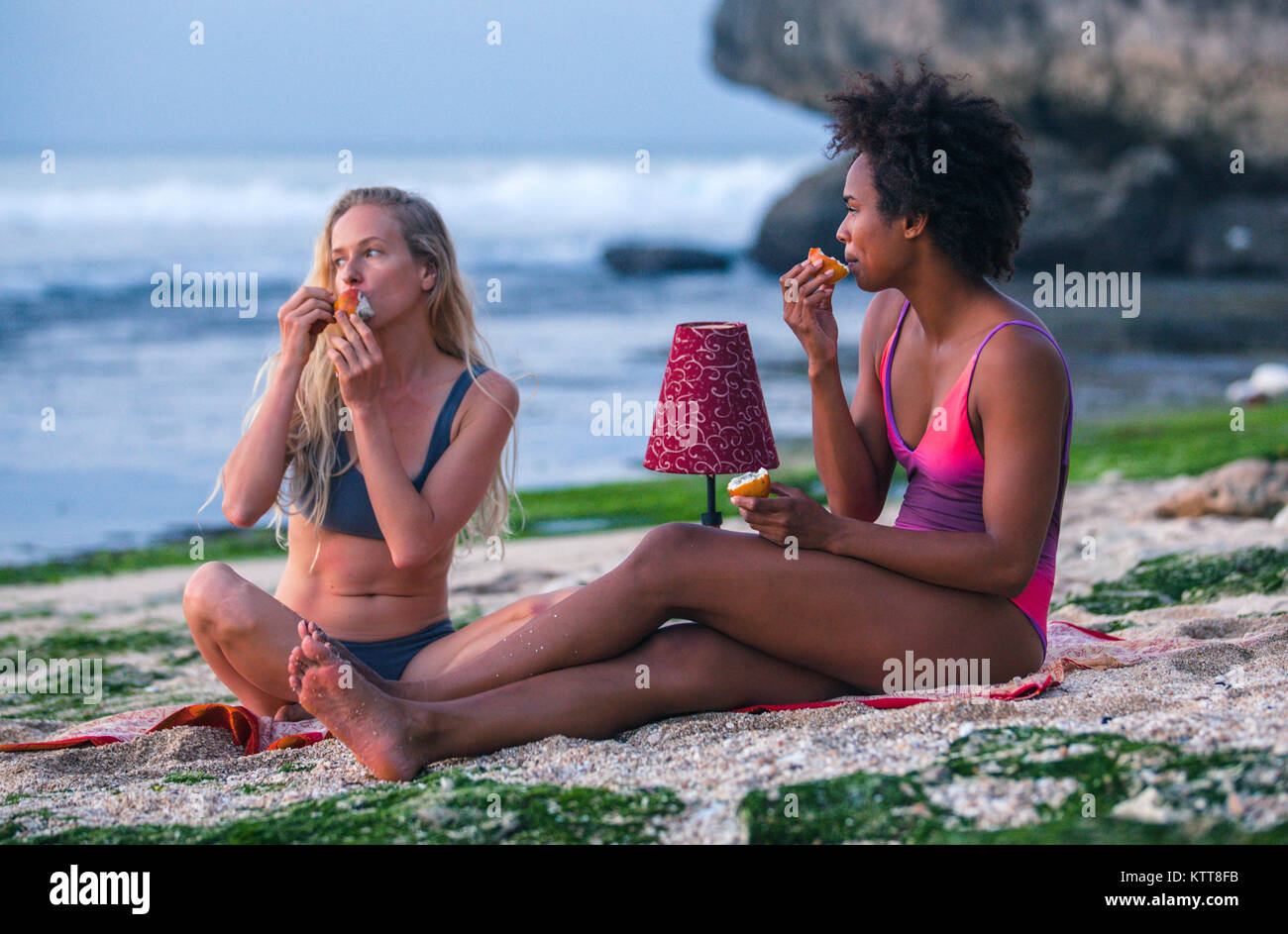 Mixed Race surfer Mädchen sich einander, Feiern am Strand essen Passionsfrüchte Stockfoto