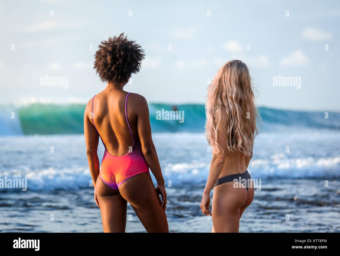 Surfer Mädchen im Bikini sehen Wellen am wunderschönen Strand von Padang Padang, Bali, Indonesien Stockfoto