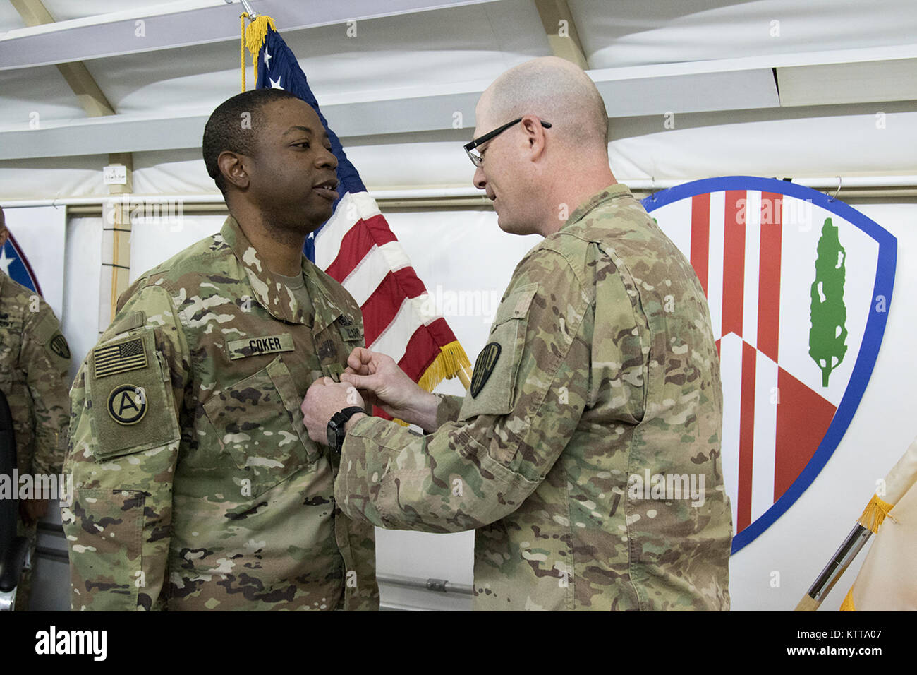 Christopher Coker, ein Brooklyn Bewohner, ist von Oberst Stephen Bousquet, 369 Sustainment Brigade Commander, während einer Zeremonie im Camp Arifjan, Kuwait, 24. April 2017 in den Rang eines Chief Warrant Officer 3 gefördert. Coker ist nach Kuwait, implementiert mit der 369 Sustainment Brigade, bekannt als der "Harlem Hölle Kämpfer", und in diesem Sommer erneut bereitstellen. (U.S. Armee Foto von Sgt. Cesar Leon) Stockfoto