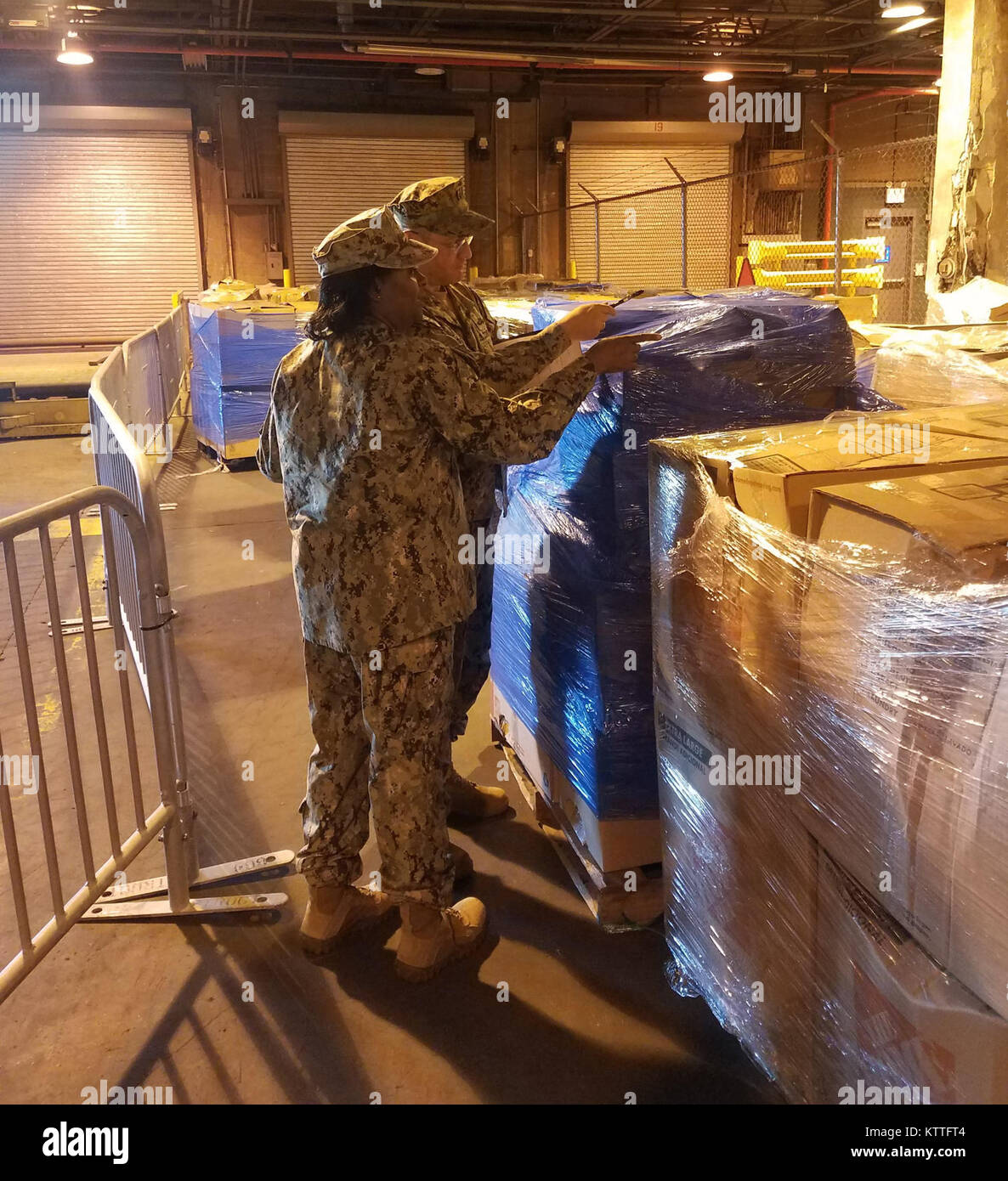 United States Coast Guard finden LT Filipp Khosh hinten und Navy Reserve Logistikspezialisten Chief Petty Officer Christopher Cintron organisieren Lieferungen für Lieferung nach Puerto Rico am JFK International Airport gespendet am Okt. 3, 2017. Beide sind auch Mitglieder der New York Naval Miliz. Naval Milizen wurden in Zustand Active Duty genannt, um Verbrauchsmaterialien für Puerto Rican relief gespendet organisieren. (New York Naval Miliz Foto von Lieutenant Commander Jay Veronko) Stockfoto