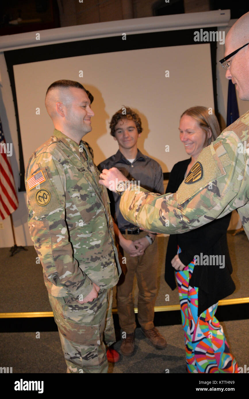 New York Army National Guard Soldat Oberstleutnant Todd Balog (links), der Kommandant der speziellen Truppen Bataillon, erhält von Oberst Stephen M. Bousquet, der Kommandant der 369. sustainment Brigade gefördert, und seiner Familie in seiner Promotion Zeremonie im Staat New York Military Museum in Saratoga Springs, New York, 8. Dezember 2017. Balog ist ein Afghanistan Veteran und Bewohner von Saratoga Springs, New York (USA Army National Guard Foto vom Kapitän Jean Marie Kratzer) Stockfoto