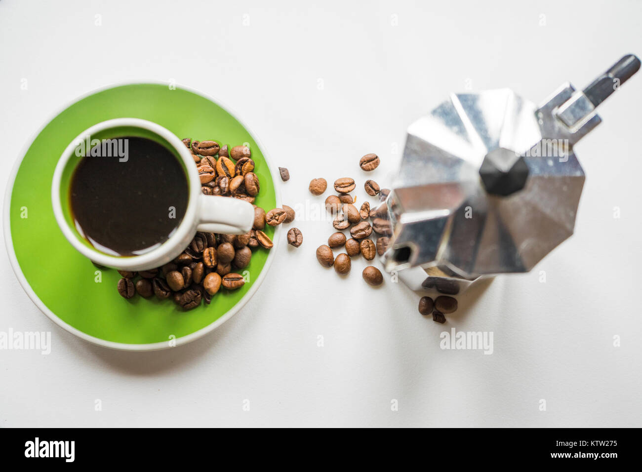 High-Angle Shot eines italienischen Moka Pot (Kaffeemaschine) und eine grüne Tasse Espresso mit Kaffeebohnen auf weißem Hintergrund Stockfoto