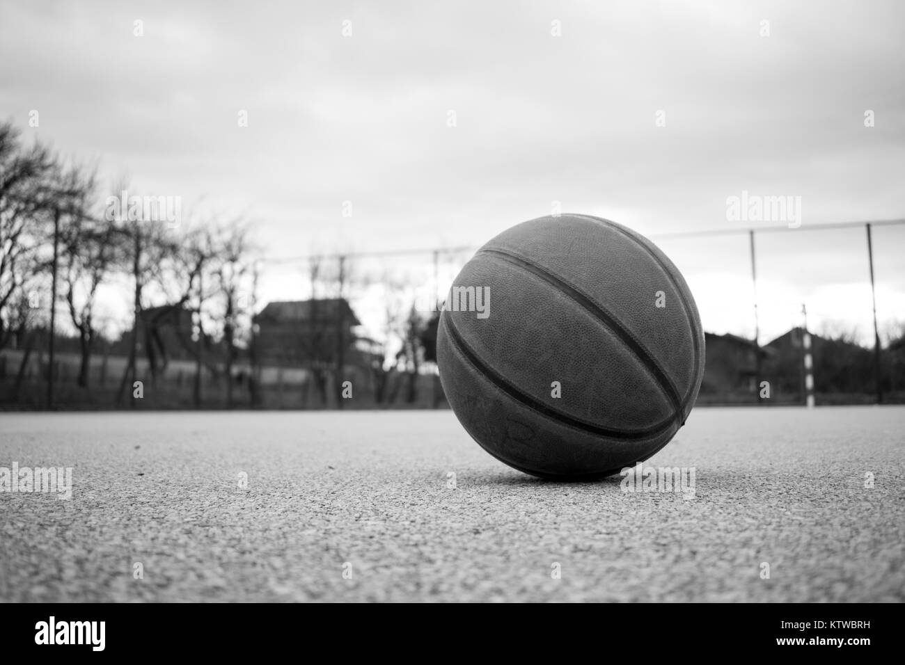 Schwarz-weiß Bild von orange Basketball mit Korb im Hintergrund. Basketball street Court Stockfoto