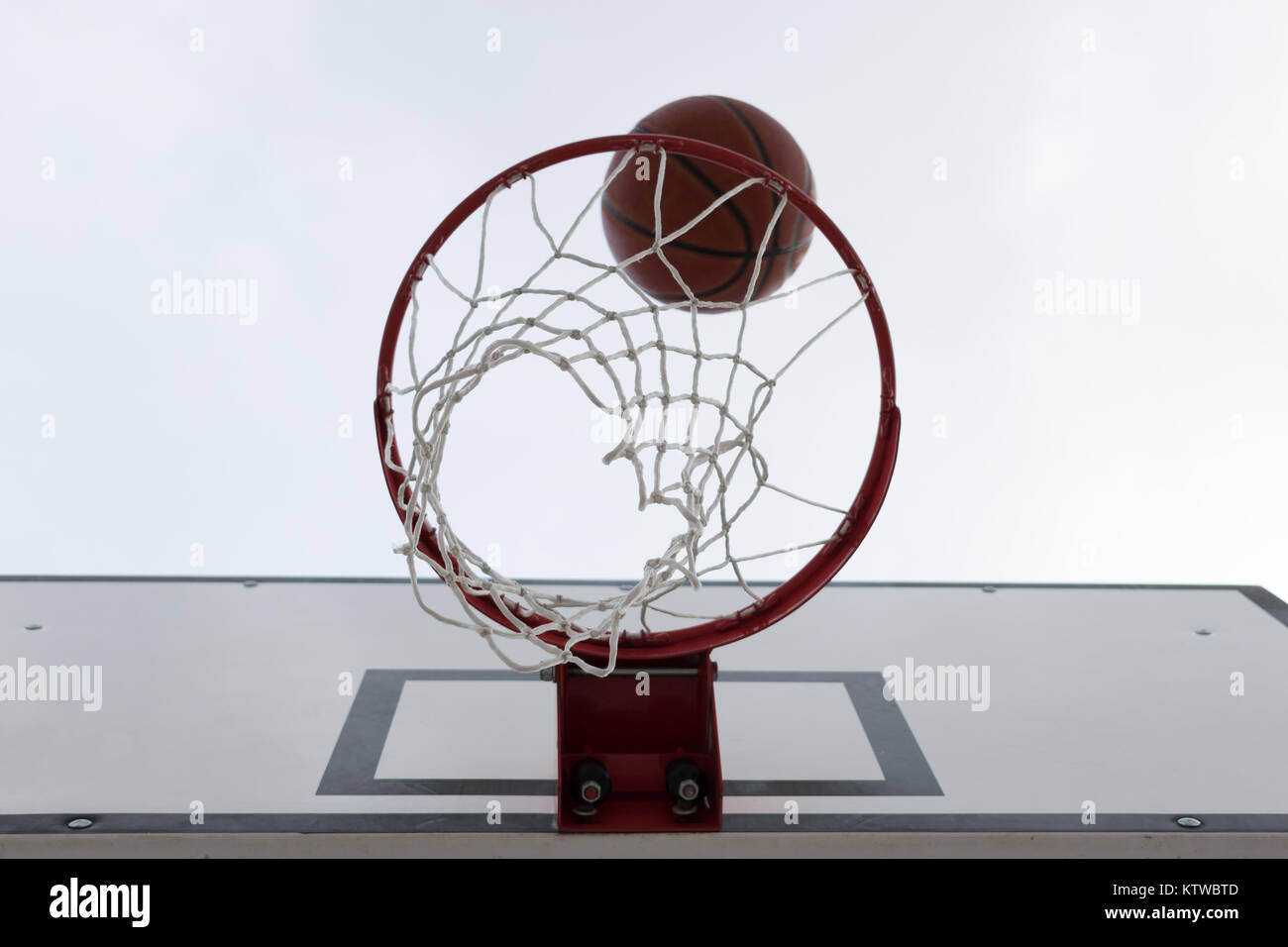 Ball innerhalb der roten Basketballkorb, Korb gegen weißen Himmel. Outdoor Basketball Court. Stockfoto