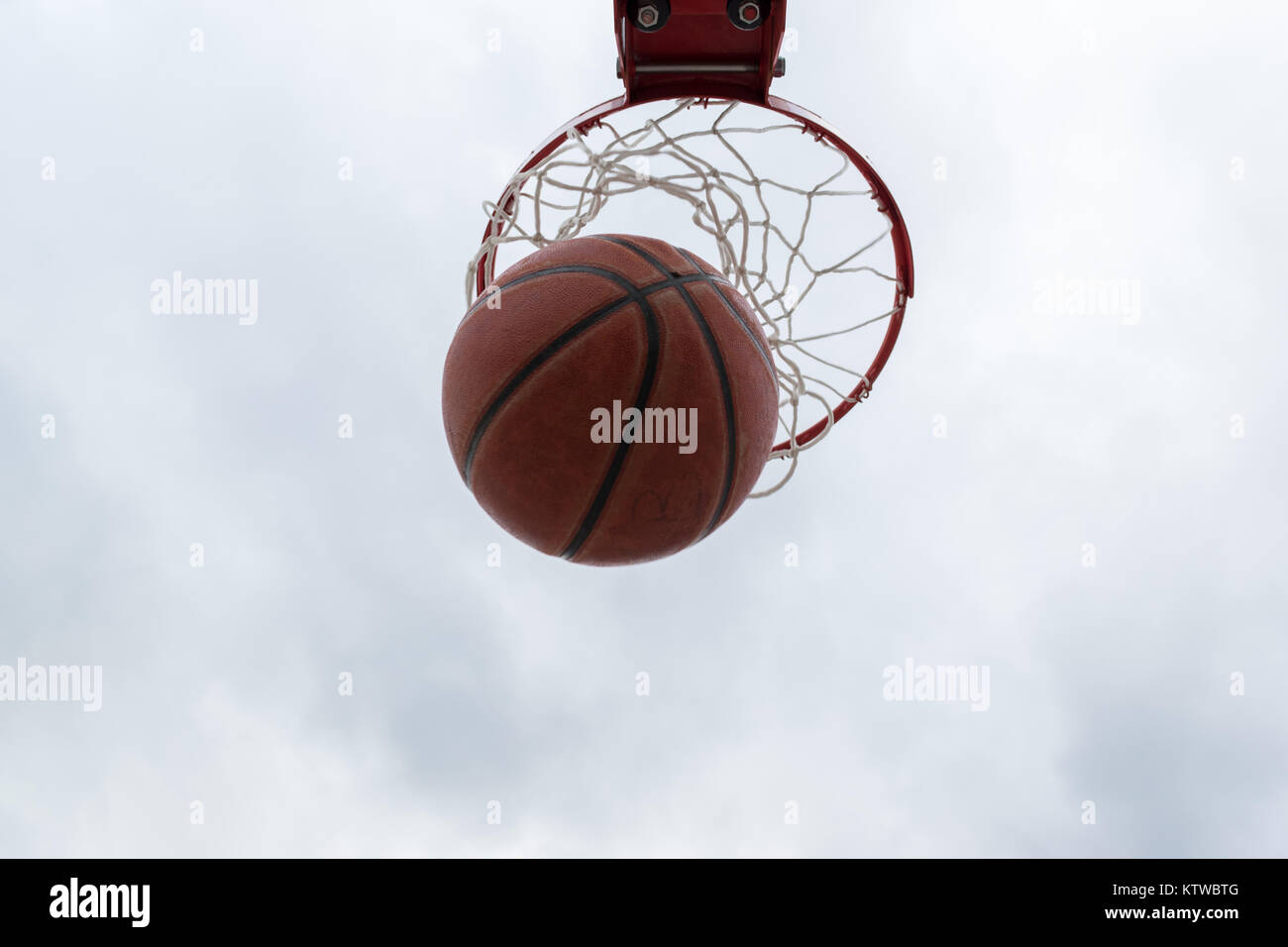 Ball innerhalb der roten Basketballkorb, Korb gegen weißen Himmel. Outdoor Basketball Court. Stockfoto